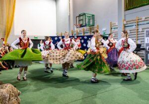 Grupa dziewczyn w góralskich strojach tańczy w kółku.