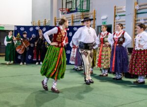 Góral i góralką tańczą. W tle kapela góralska.