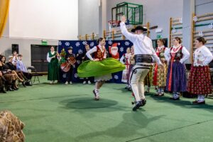 Góral i góralką tańczą. W tle kapela góralska.