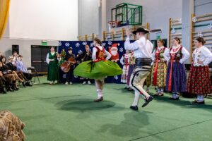 Góral i góralką tańczą. W tle kapela góralska i góralki.