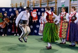 Góral i góralką tańczą. W tle kapela góralska i góralki.