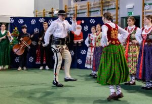 Góral i góralką tańczą. W tle kapela góralska i góralki.