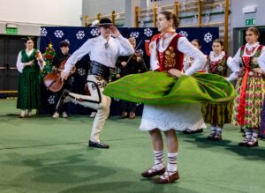 Góral i góralką tańczą. W tle kapela góralska i góralki.