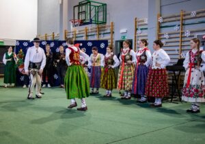 Góral i góralką tańczą. W tle kapela góralska i góralki.