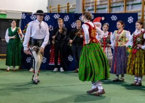 Góral i góralką tańczą. W tle kapela góralska i góralki.