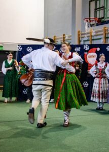 Góral i góralką tańczą. W tle kapela góralska i góralki.