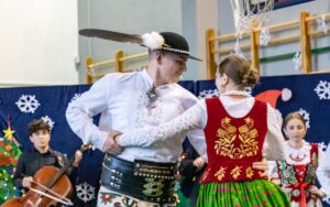 Góral i góralką tańczą. W tle kapela góralska i góralki.