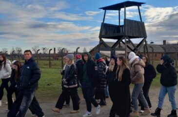 Uczniowie przechodzą przez obóz Auschwitz-Birkenau w Oświęcimiu. W tle wieża strażnicza.