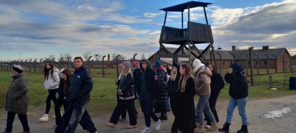 Uczniowie przechodzą przez obóz Auschwitz-Birkenau w Oświęcimiu. W tle wieża strażnicza.