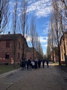 Uczniowie idą między barakami w obozie Auschwitz-Birkenau w Oświęcimiu