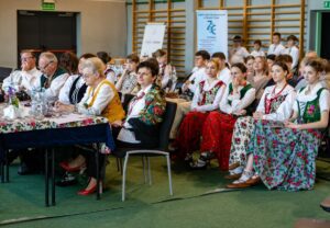 Na pierwszym planie jury a za nim publiczność w strojach regionalnych.
