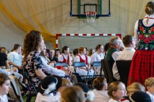 Zdjęcie publiczności, na środku kadru trzy uczennice w strojach regionalnych.