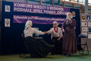 Kolejne występy uczestników konkursu – trzy uczennice w strojach regionalnych występujący w scence rodzajowej.