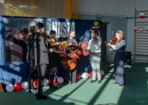 17. Na tle scenografii występuje zespół muzykantów.