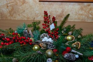 Zbliżenie na gipsową, dziecięca figurka śpiącego Jezusa przyozdobiona świątecznymi ozdobami.