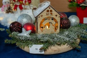 Zbliżenie na stroik, którego głównym elementem jest drewniana ministajenka.