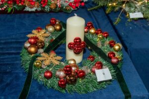 Stroik w formie jedlinowego wianka przyozdobiony czerwonymi minibombkami. i świecą pośrodku.