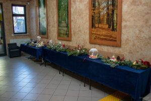 Ogólny widok na stoły z granatowym płótnem, na którym ustawione są stroiki.