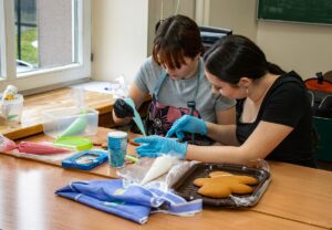 Dwie uczennicy ozdabiają pierniki lukrem.