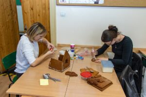 Dwie uczennice wykonują piernikową stajenkę.