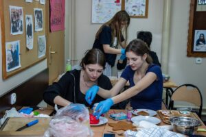 Dwie uczennice przy pracy zdobniczej pierników czerwonym lukrem.