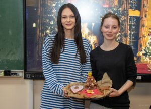 Dwie uczennice prezentują piernikową choinkę.