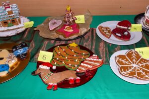 Zbliżenie na piernikowe dzieła - w centrum piernik w kształcie jamnika z czerwonymi bucikami i czapeczką..