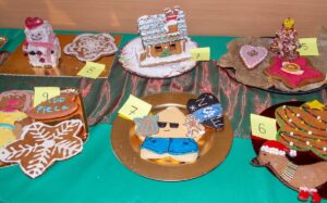 Zbliżenie na piernikowe dzieła - domek , serduszka, gwiazdy i na środku zdjęcia postać w niebieskich krótkich spodenkach..