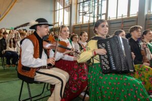 Akordeonistka i skrzypek w strojach regionalnych wspomagają występ klasy 1 RS.