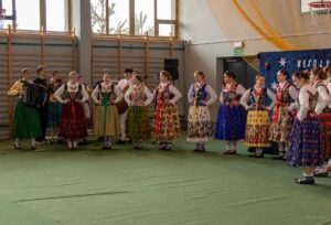 Na scenie w półkolu ustawione dziewczęta z zespołu góralskiego śpiewające kolędę.