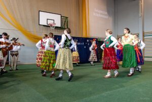 Dziewczęta z zespołu góralskiego w kółeczku tańczą taniec góralski.