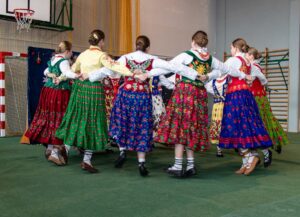 Następne zdjęcie dziewczęta z zespołu góralskiego, które w kółeczku tańczą taniec góralski.