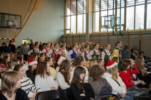 Za idąca akordeonistką podążają dziewczęta w strojach regionalnych.