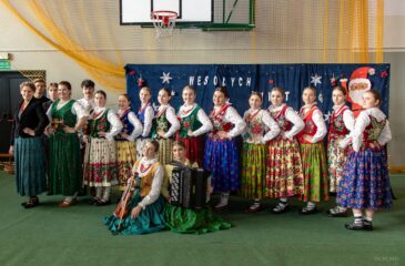 Uśmiechnięci członkowie kapeli i dziewczęta z zespołu góralskiego wraz z opiekunką.