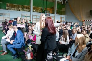 Uczennice i uczniowie klas piątych żegnają nauczycieli symbolicznymi podarunkami, którymi są różyczki w doniczkach.
