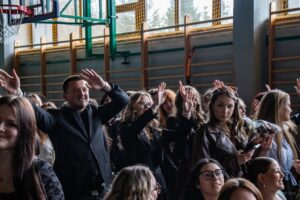 Zbliżenie na radośnie machających absolwentów szkoły.