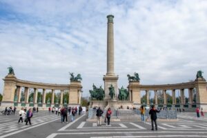 Pomnik na Placu Bohaterów, po środku wysoka kolumna po obu jej stronach postumenty z rzeźbami i kolumnami.