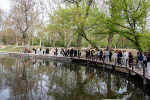 Uczniowie idący brzegiem stawku w parku.
