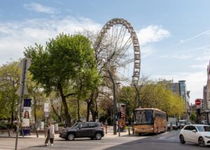 Budapesztańska ulica a w tle za drzew wyłania się wielkie koło "Budapest Eye".
